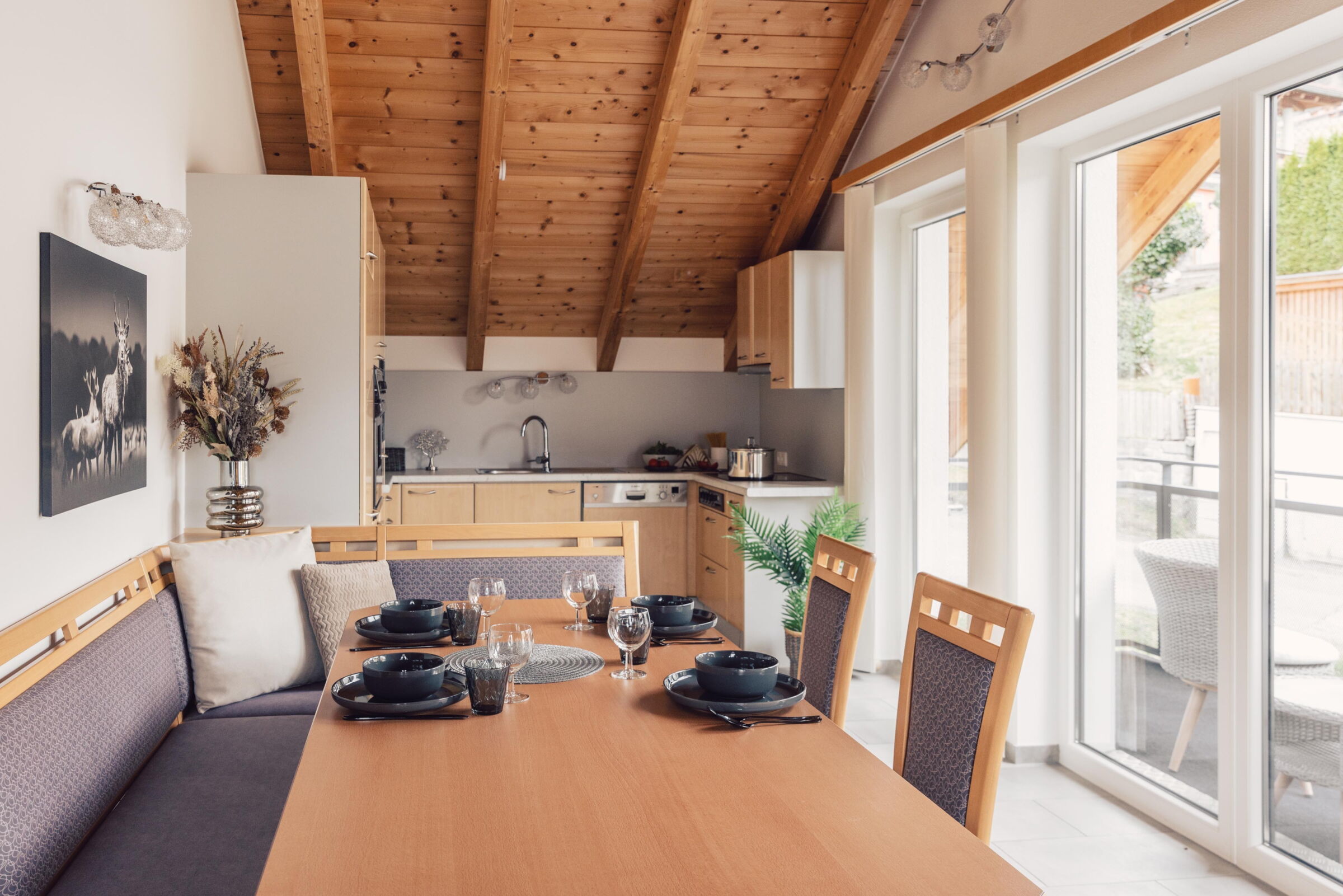 Helle Küche mit Holztisch und gedecktem Geschirr in alpinem Ambiente.