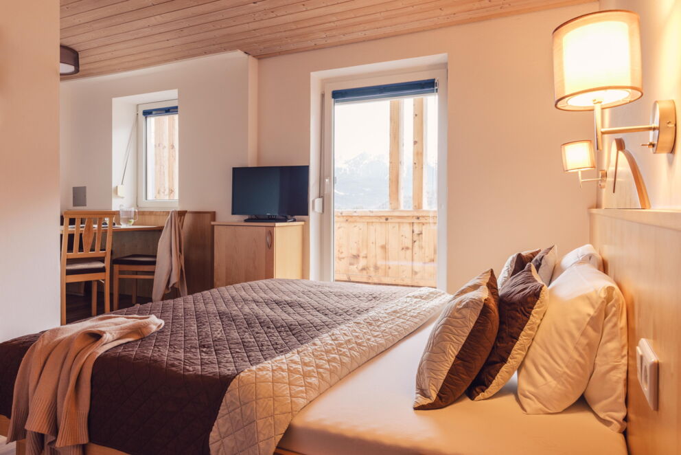 Bright room with wooden accents, large bed, desk and window view.