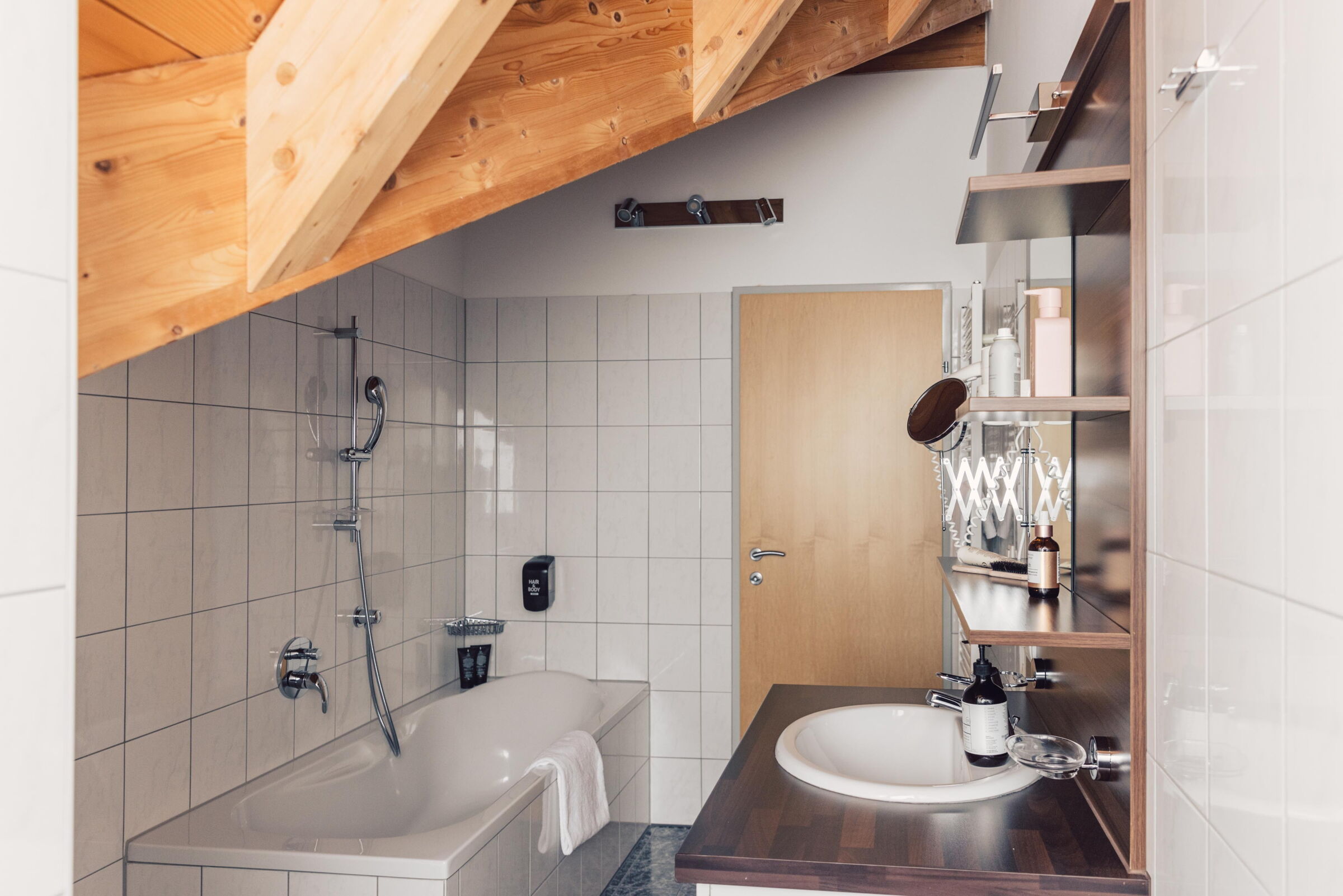 Badezimmer mit Badewanne, Holzelementen und modernen Annehmlichkeiten für entspannte Momente.