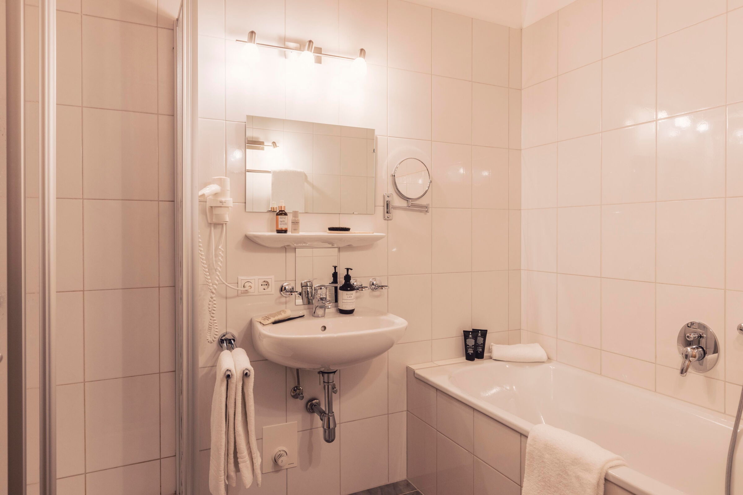 Modernes weißes Badezimmer mit Badewanne, Spiegel und Handtüchern.