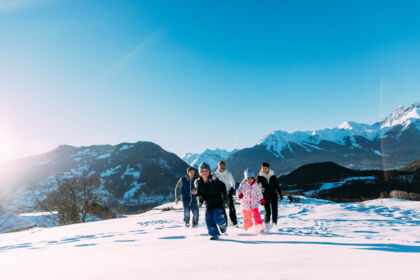 Familie genießt fröhlich den Schnee vor majestätischen Tiroler Alpen.