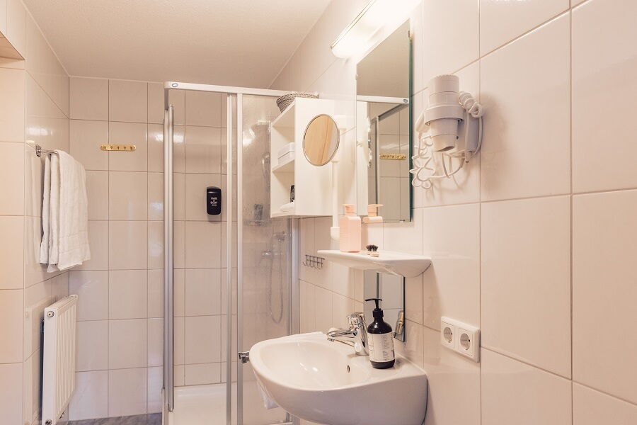 Helles, modernes Badezimmer mit Dusche und Waschbecken in einem kinderfreundlichen Hotel.