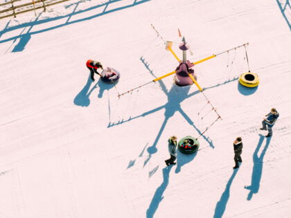 Kinder spielen mit Schneereifen auf einer winterlichen Spielfläche im Freien.