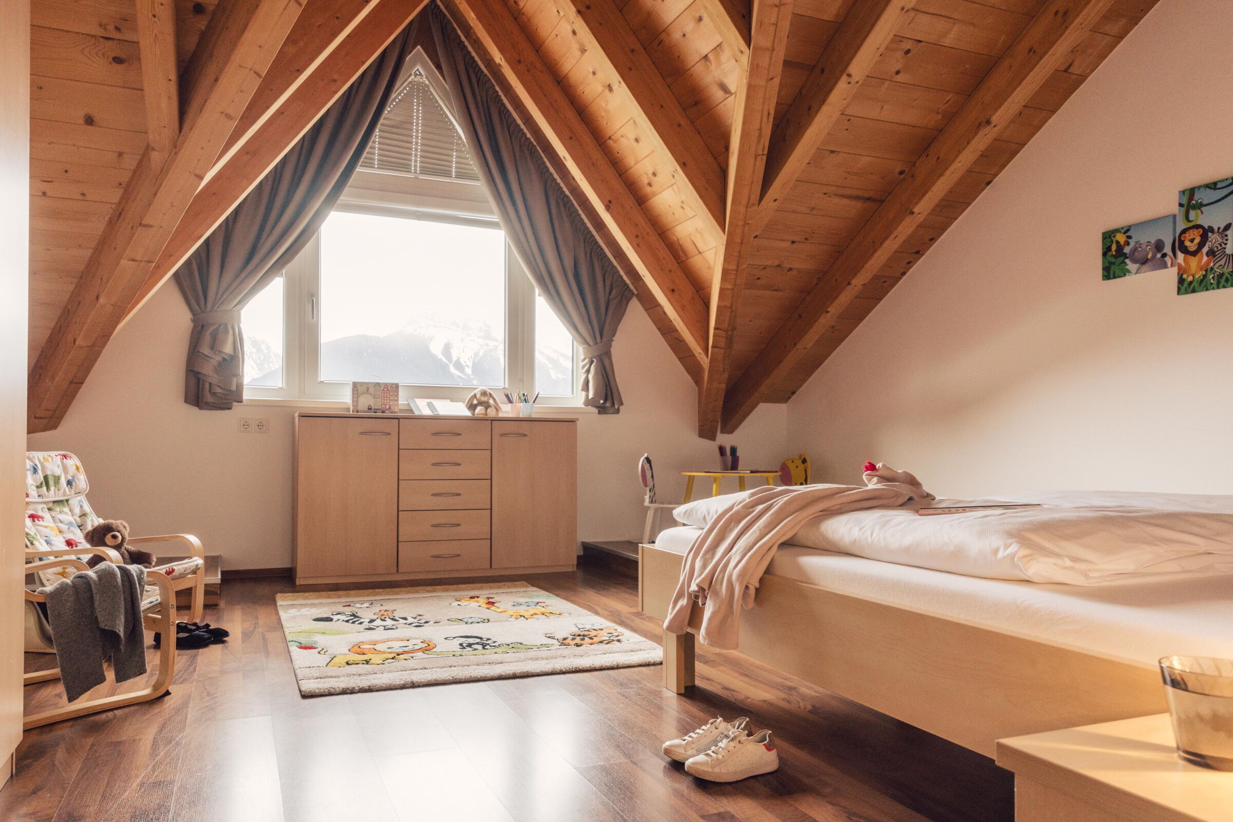Helles Zimmer mit Holzdecke, Bett und kuscheligen Details für die ganze Familie.