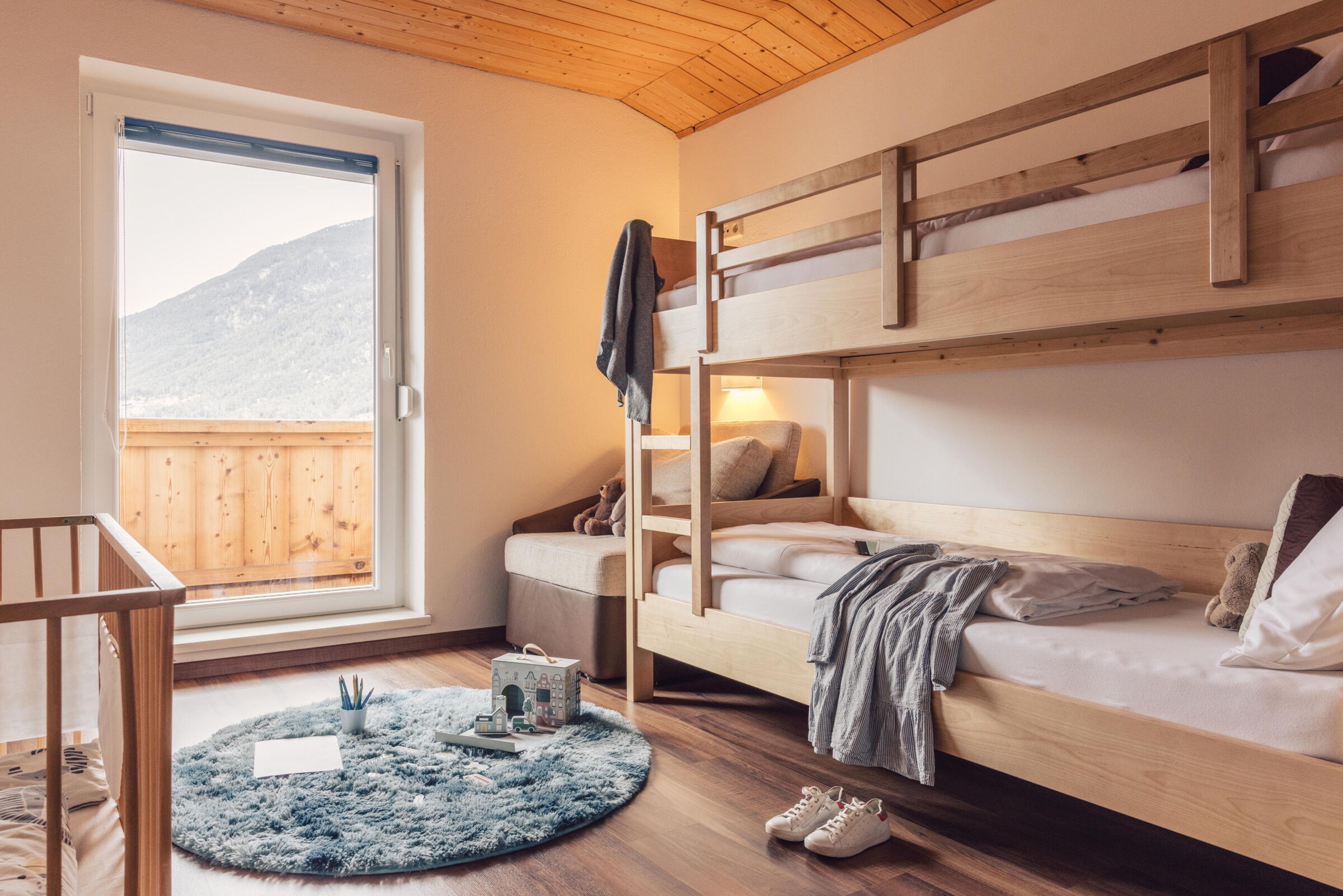 Helles Zimmer mit Hochbett, Spielzeug und Bergblick im Tiroler Familienhotel.