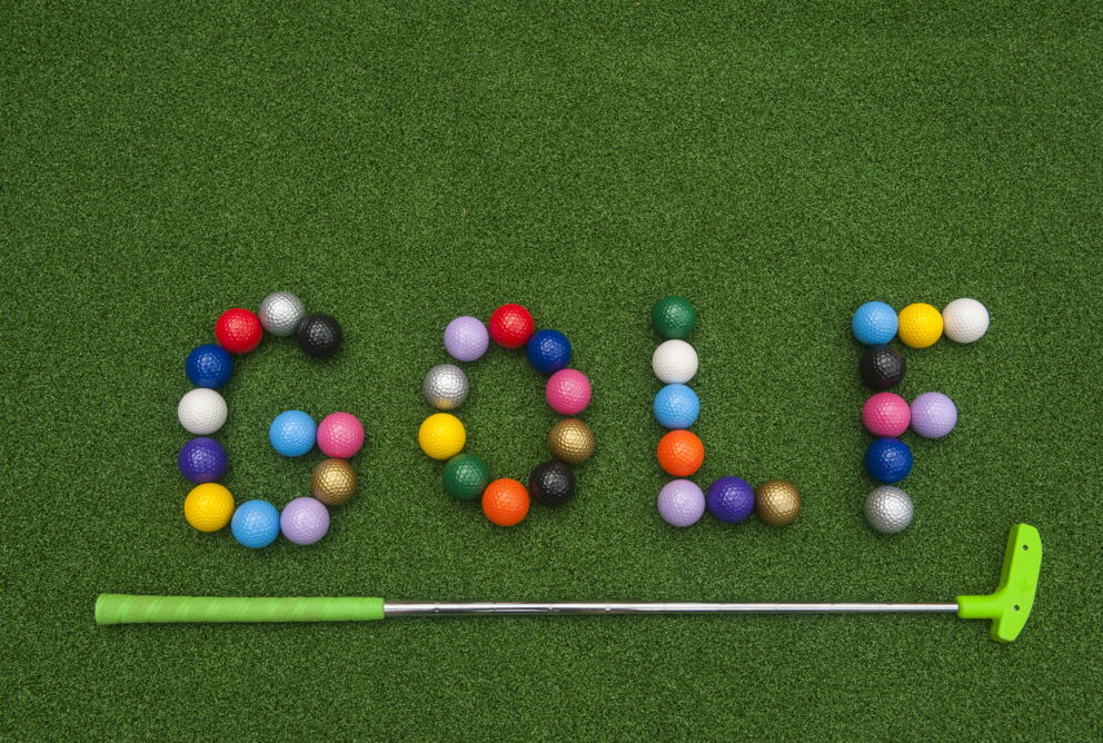 Colorful golf balls form the word "GOLF" on green grass.