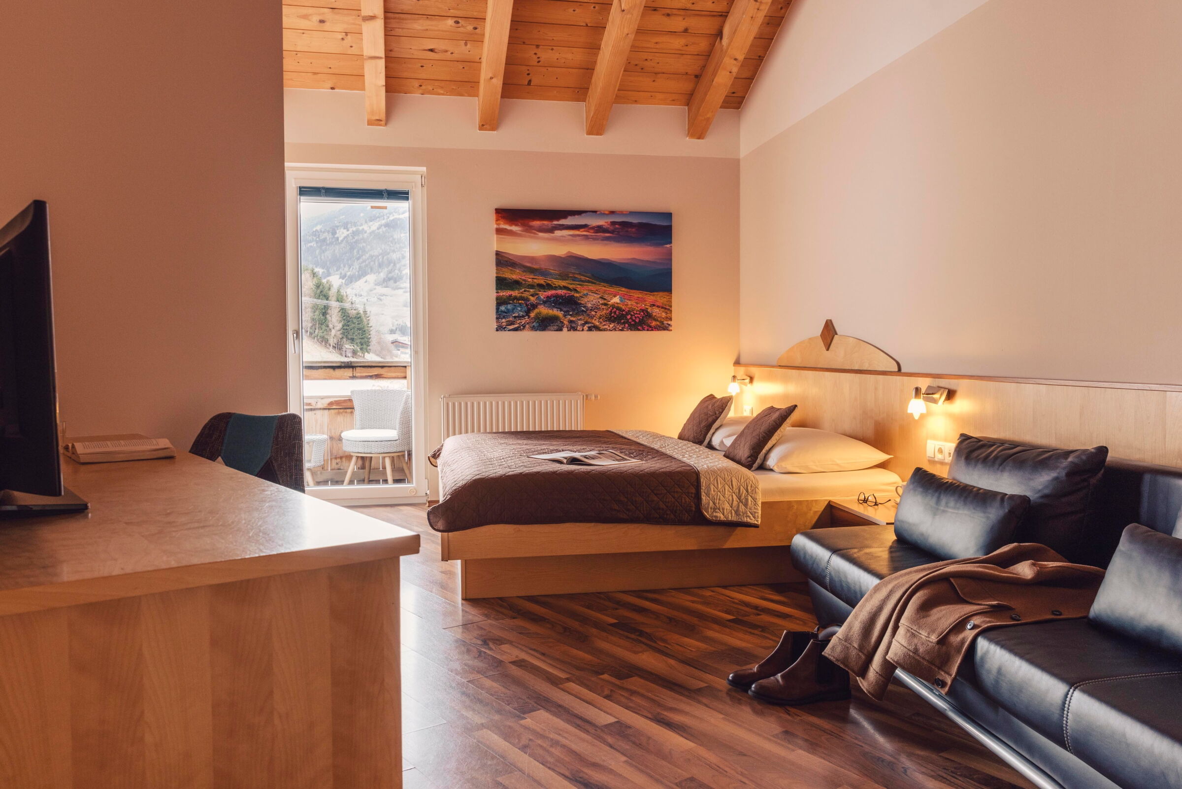 Helles Schlafzimmer mit Holzdecke, Doppelbett und Balkonblick auf Tiroler Berge.