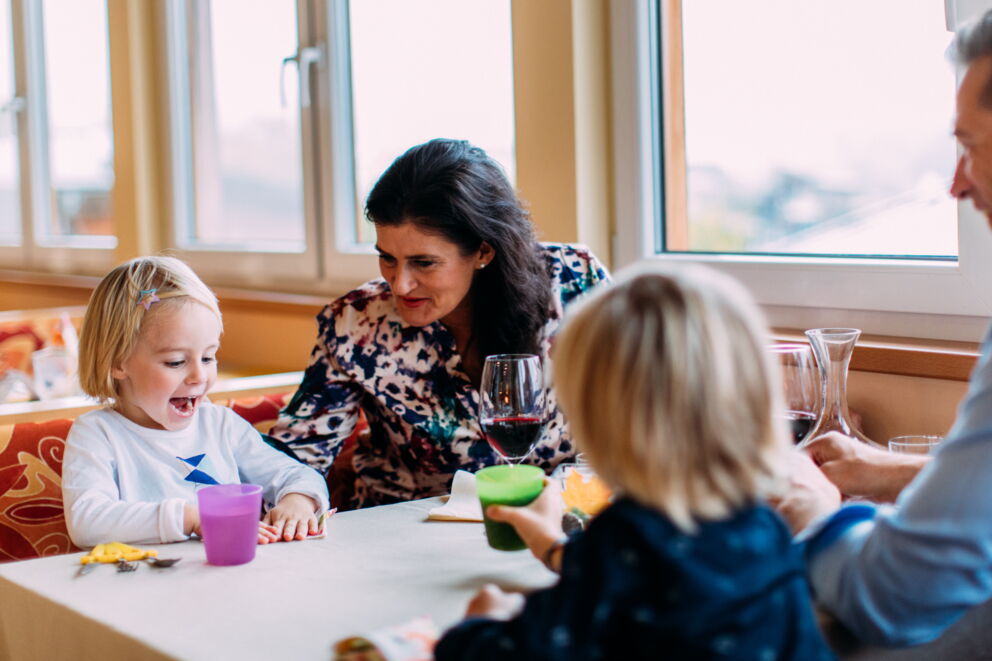 Family sitting at the table and enjoying a meal together at the Kinderhotel.