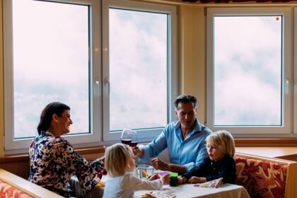 Family enjoying time together at the table with drinks and a view out of the window.