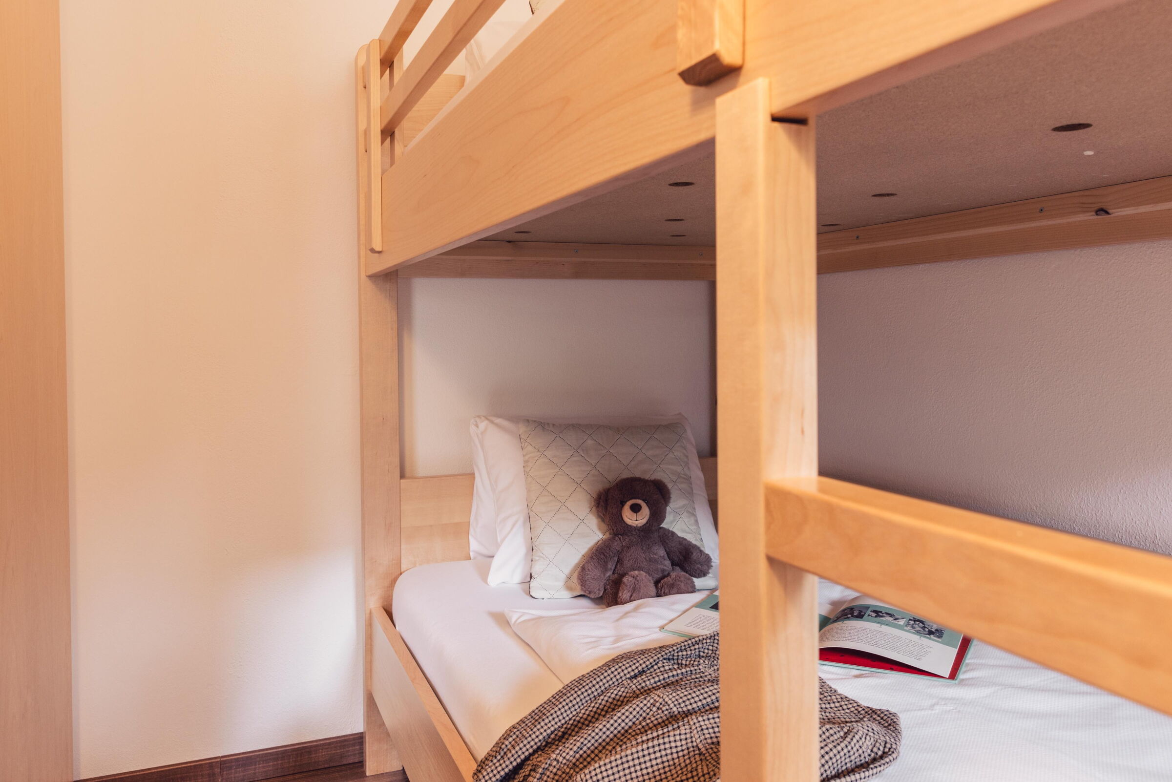 Hochbett mit Kuscheltier und Buch für gemütliche Kinderabende im Kinderhotel.
