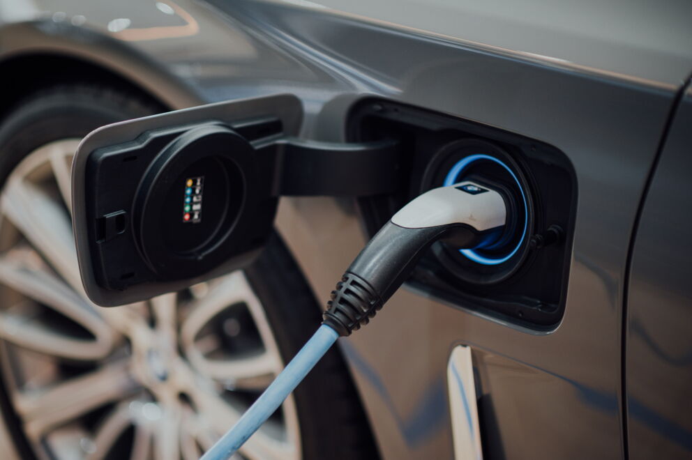 Electric car being charged with charging cable, view from the side.