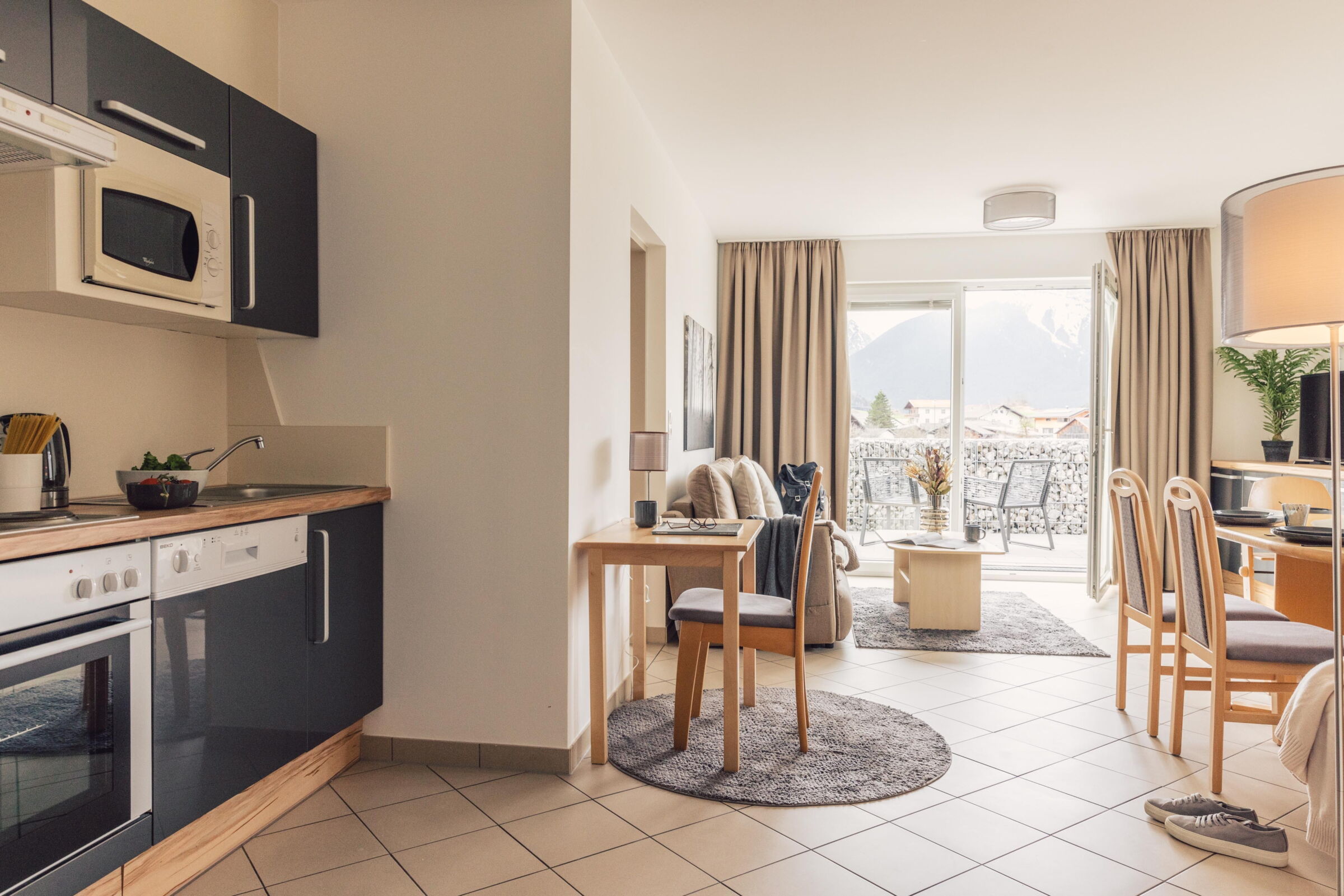 Modern kitchen and cozy living room with mountain view and balcony.