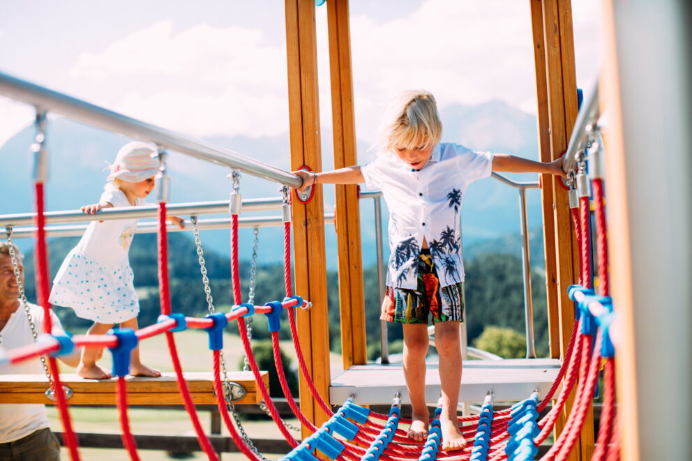 Children play happily on a climbing frame outdoors.