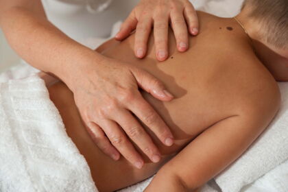 Child receives a relaxing back massage, hands massage gently.