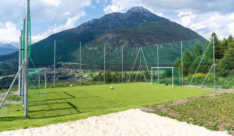 Fußballplatz mit Toren vor beeindruckendem Bergpanorama und grünem Tal