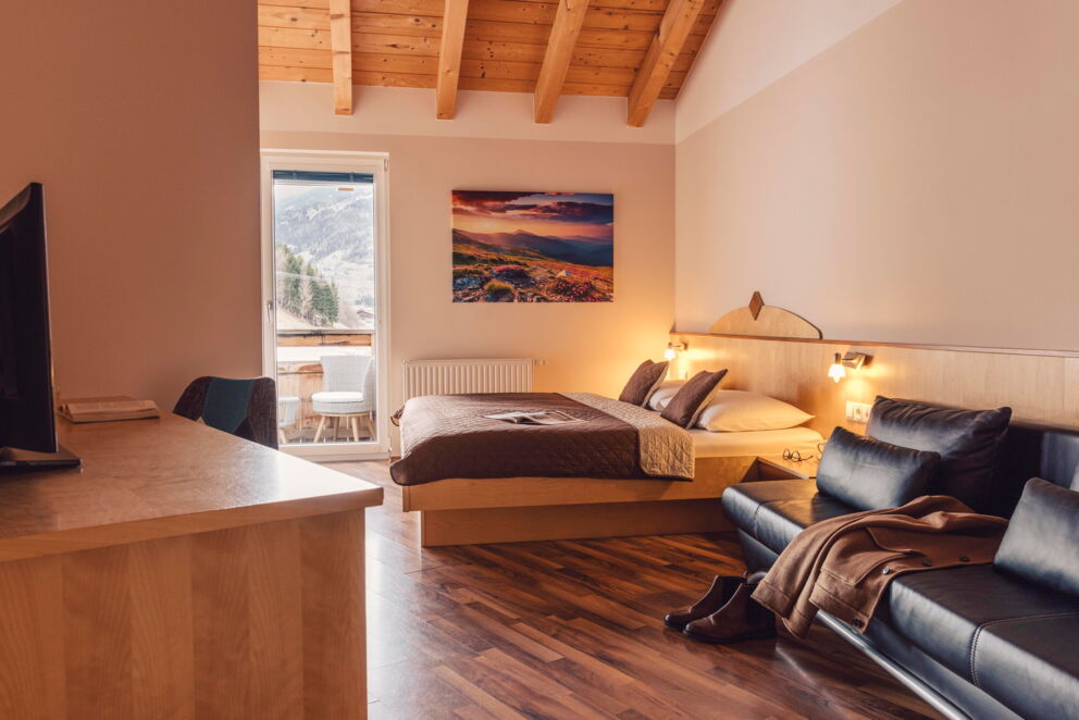 Bright bedroom with wooden ceiling, double bed and balcony view of the Tyrolean mountains.