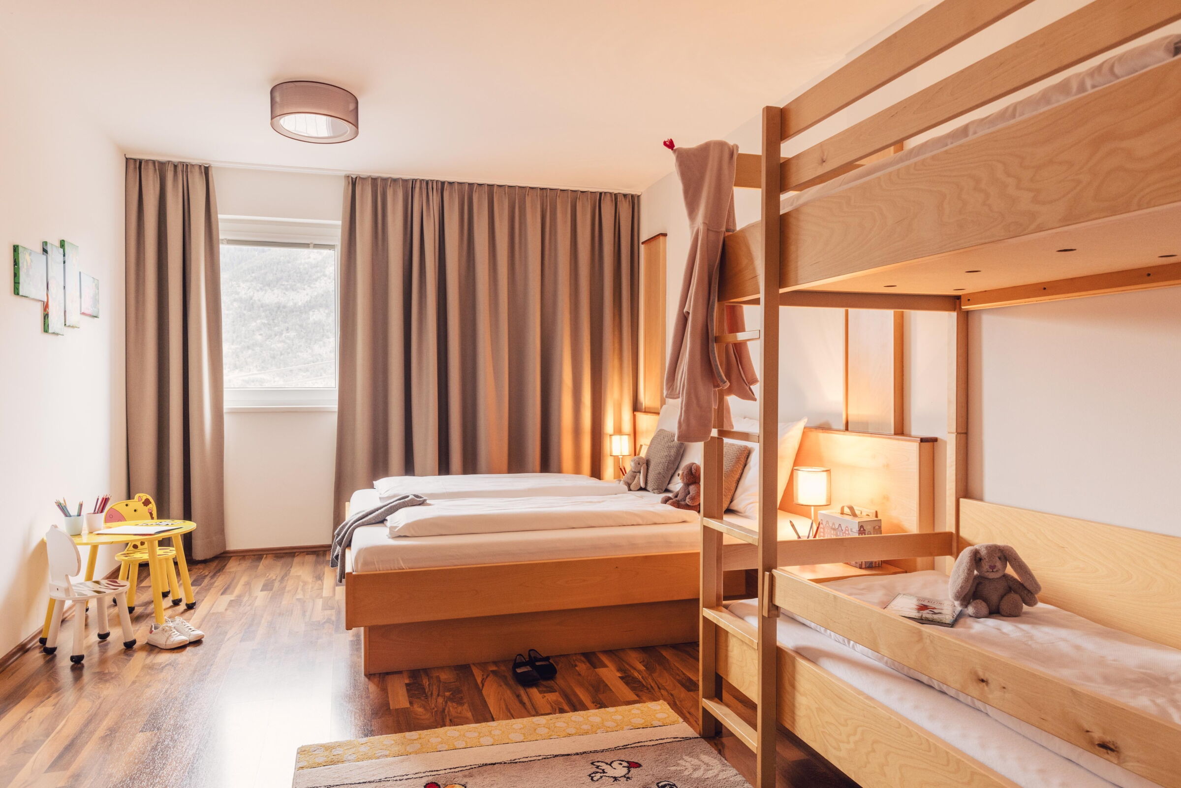 Bright room with bunk bed, double bed and children's table for creative play.