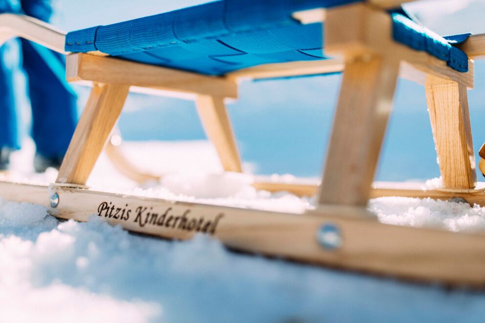 Wooden toboggan with blue seat on a snow-covered surface in the Pitztal valley