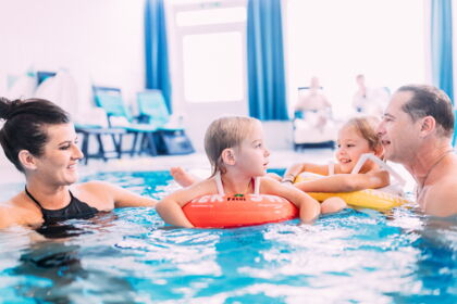 Familie genießt gemeinsamen Badespaß im Hotelpool mit Schwimmreifen.