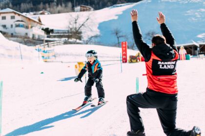 Child learns to ski with instruction on a sunny slope in a winter paradise.