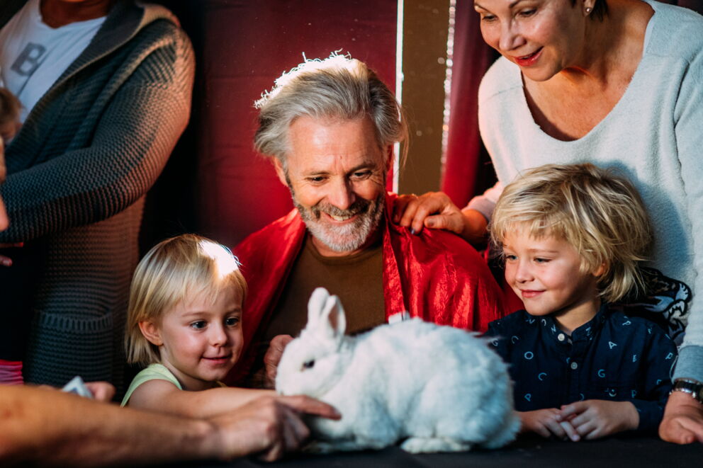 The family smiles at a white rabbit on the table.