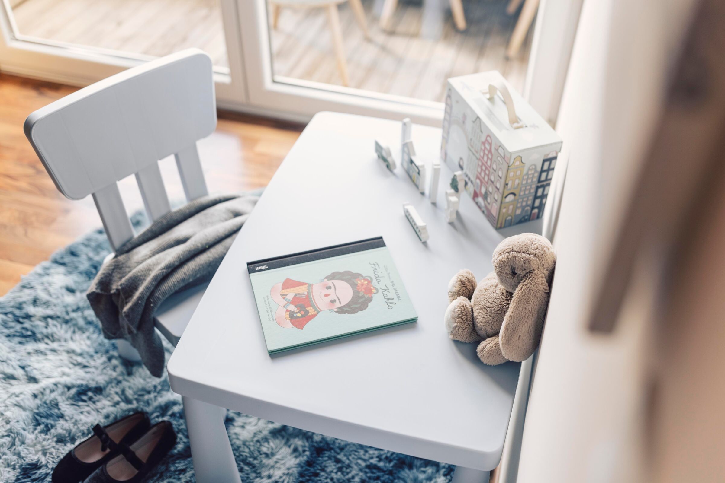 Children's table with coloring book, pencils and soft toy on a soft carpet.
