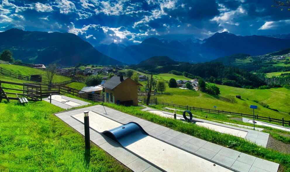 Mini golf course with a breathtaking mountain panorama under a dramatic sky in Tyrol.