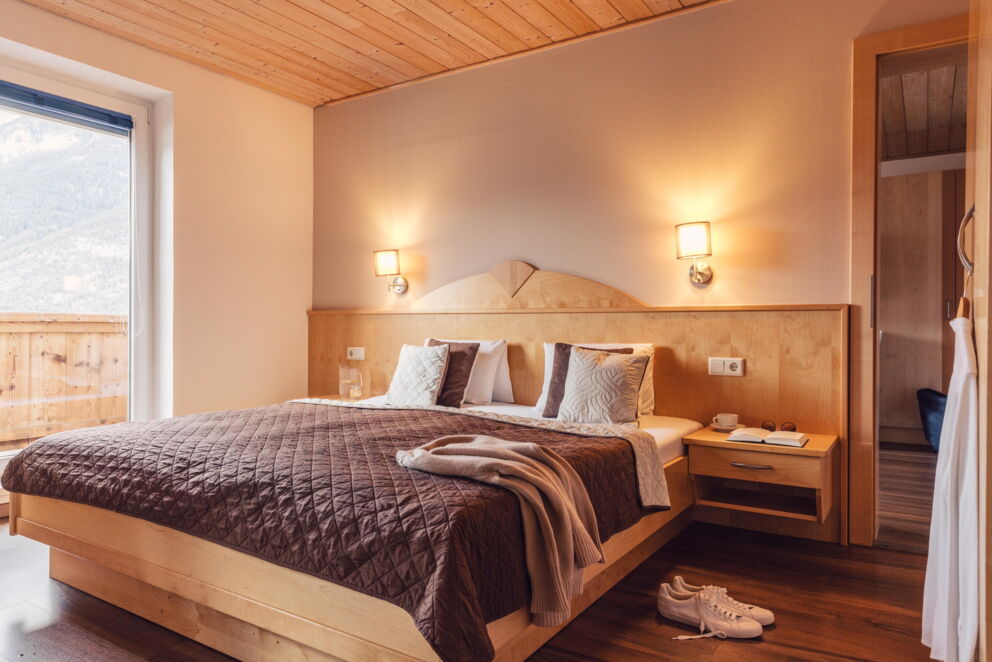 Bright wooden room with cozy lighting and mountain view through large window.