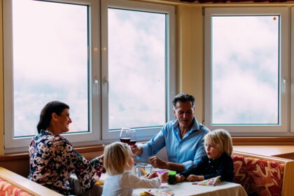 Family enjoying time together at the table with drinks and a view out of the window.