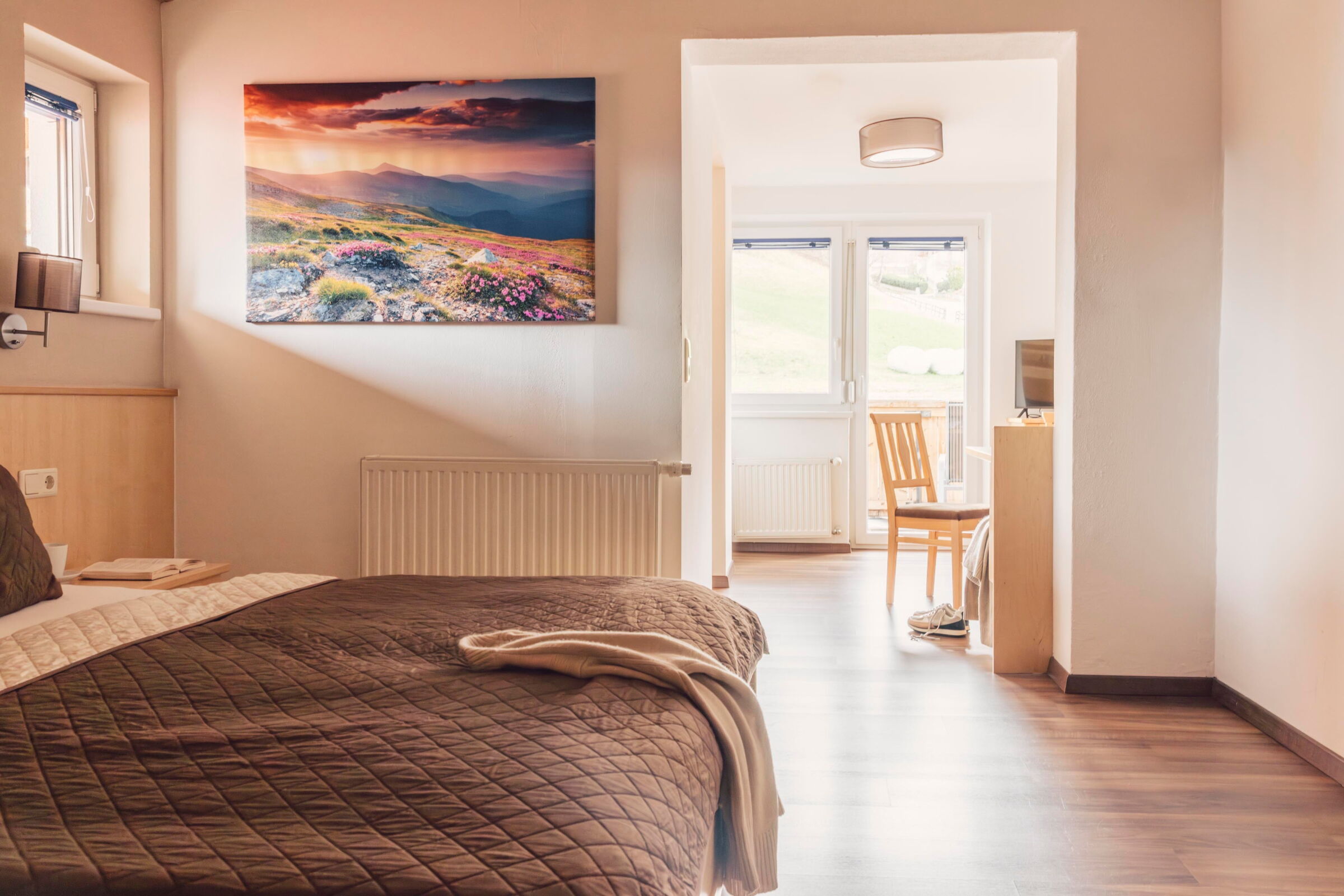 Helles Familienzimmer mit Doppelbett, Gemälde und Balkon mit Blick auf Tirol.