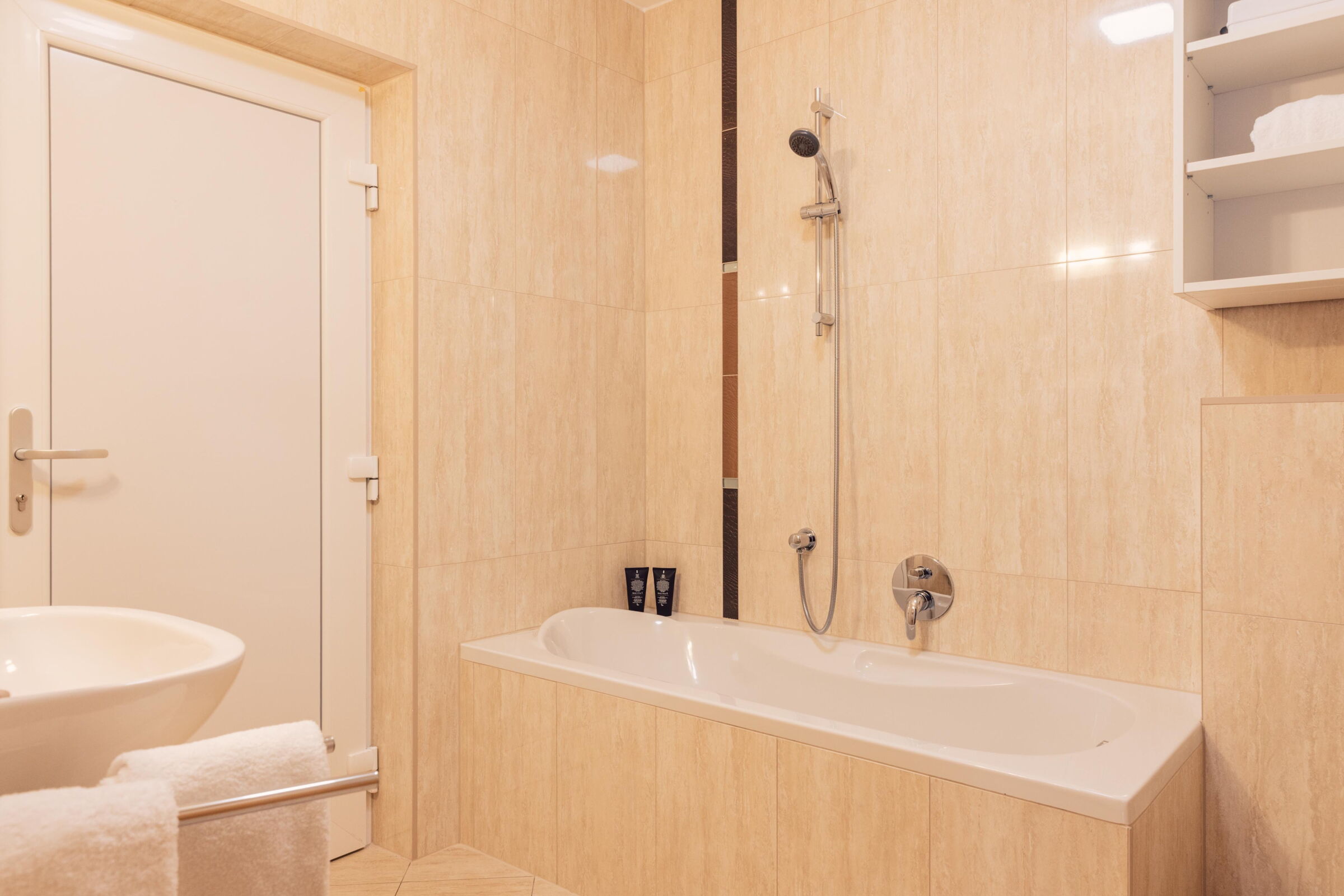 Modern bathroom with bathtub, shower head, washbasin and towel rail.