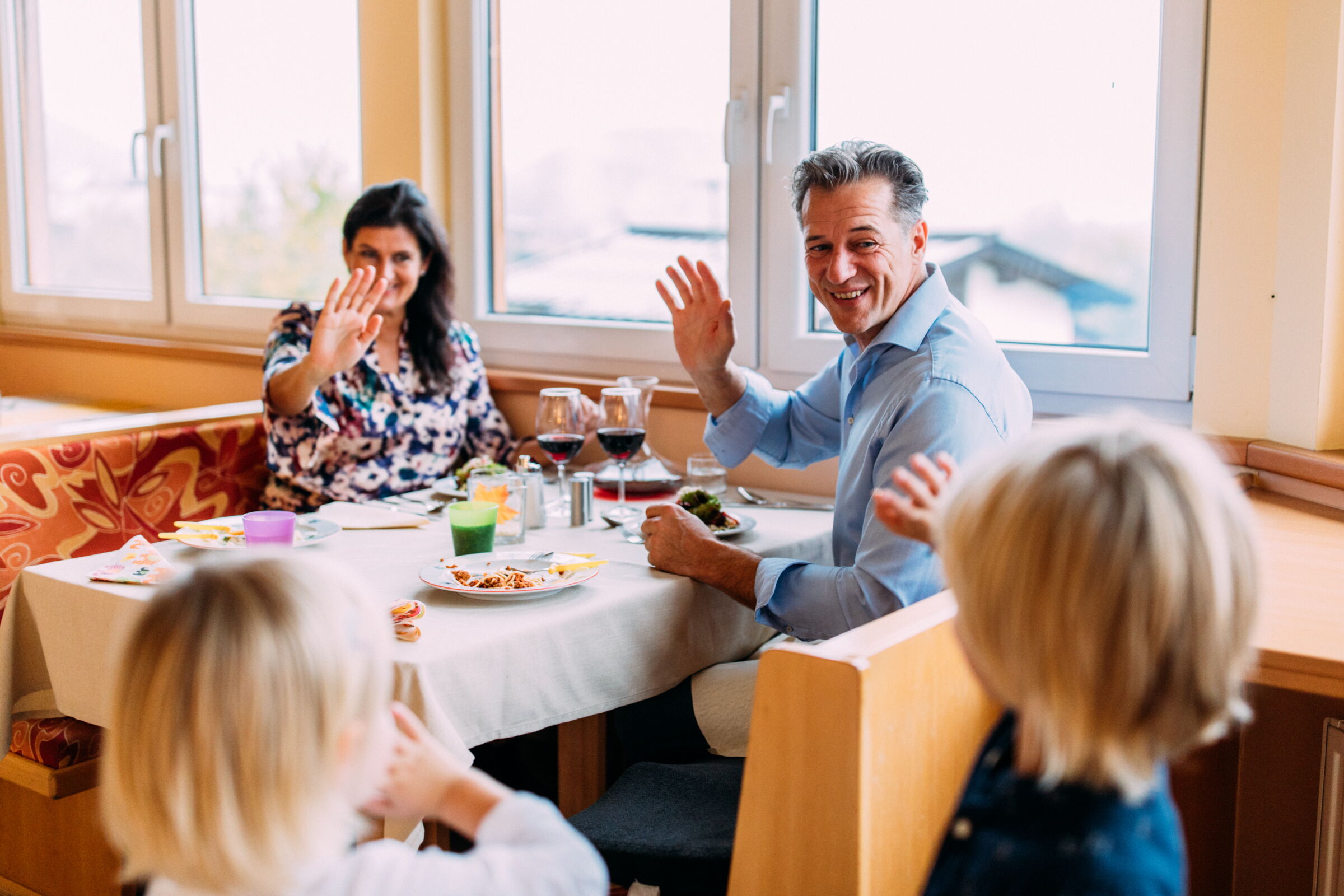 Family enjoys a meal together at the table in a cozy, light-flooded room.