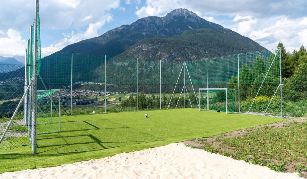 Fußballplatz mit Toren vor beeindruckendem Bergpanorama und grünem Tal