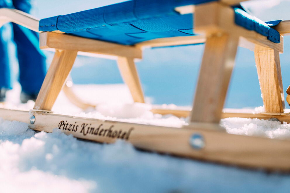 Holzrodel mit blauer Sitzfläche auf verschneiter Fläche im Pitztal