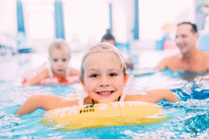 Children laugh in the pool as they splash around in glowing swimming rings.